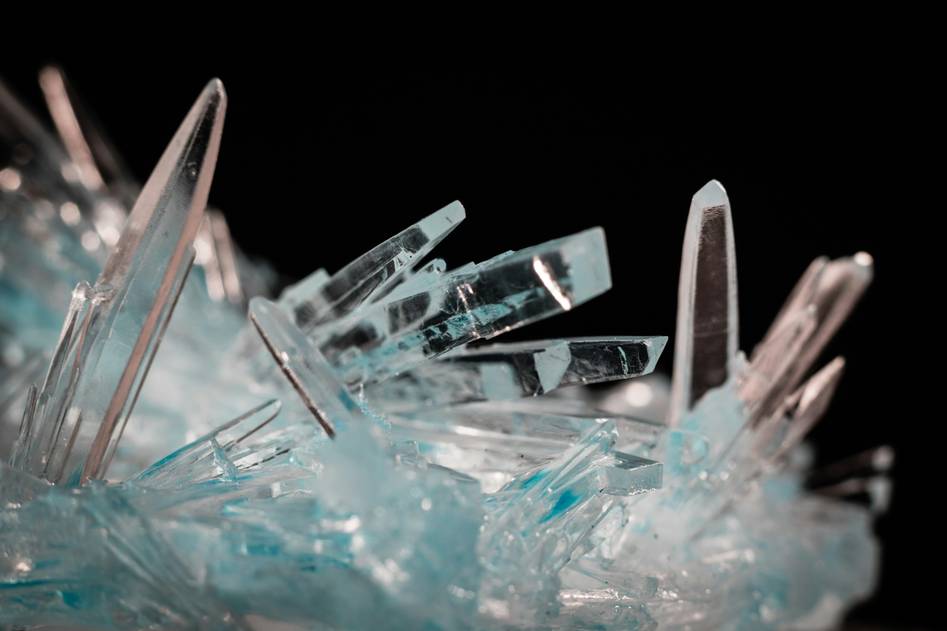 Founder holding raw organic crystals beside natural skincare ingredients on wooden surface