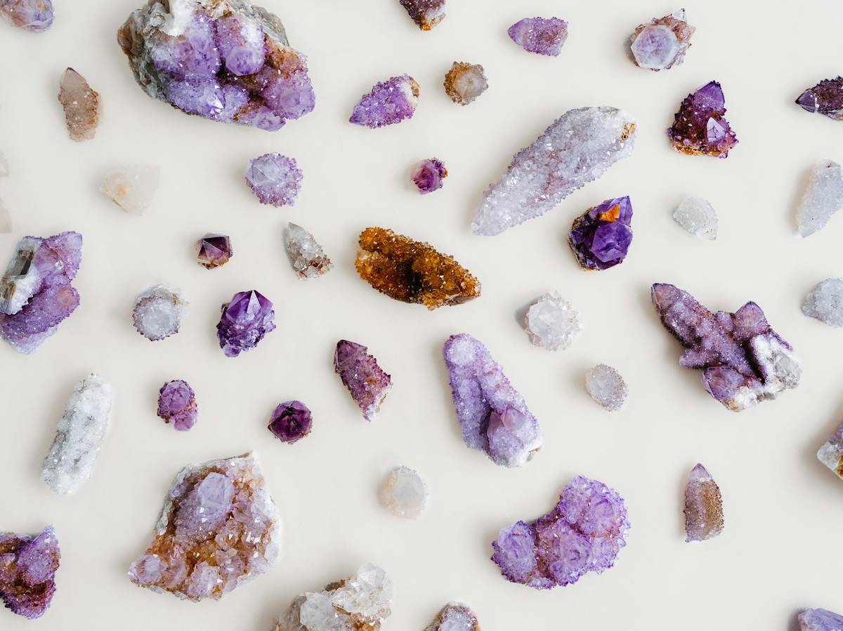 Assorted decorative crystals for crafts displayed on a wooden tray, including raw quartz points, tumbled amethyst, and rose quartz chips